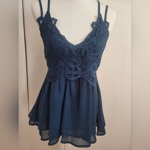 ,Feager blue top with crocheted flowers on top .